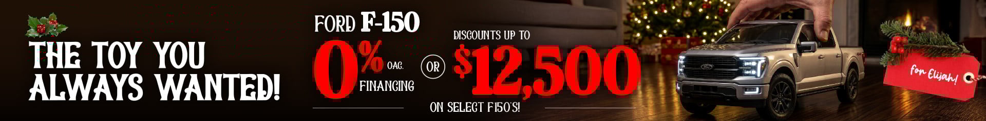 A hand positions a toy-like silver Ford F-150 on a hardwood floor in front of a sparkling Christmas tree. Bold holiday graphics highlight 0% financing OAC or up to twelve thousand five hundred dollars in discounts on select F-150 models, with a festive red tag reading “for Elijah!”